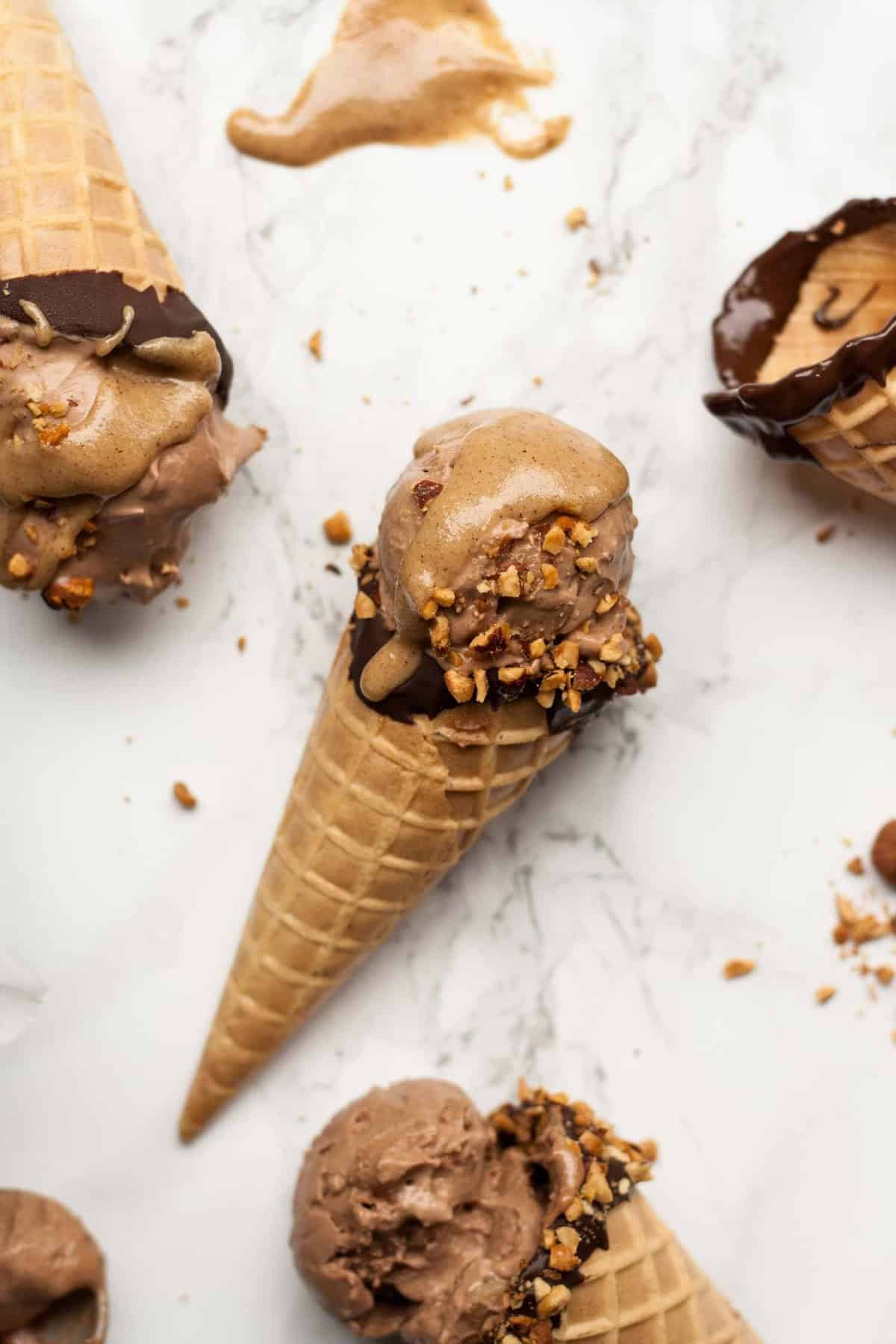 Close up of mocha ice cream cone with nut butter and nuts on top.