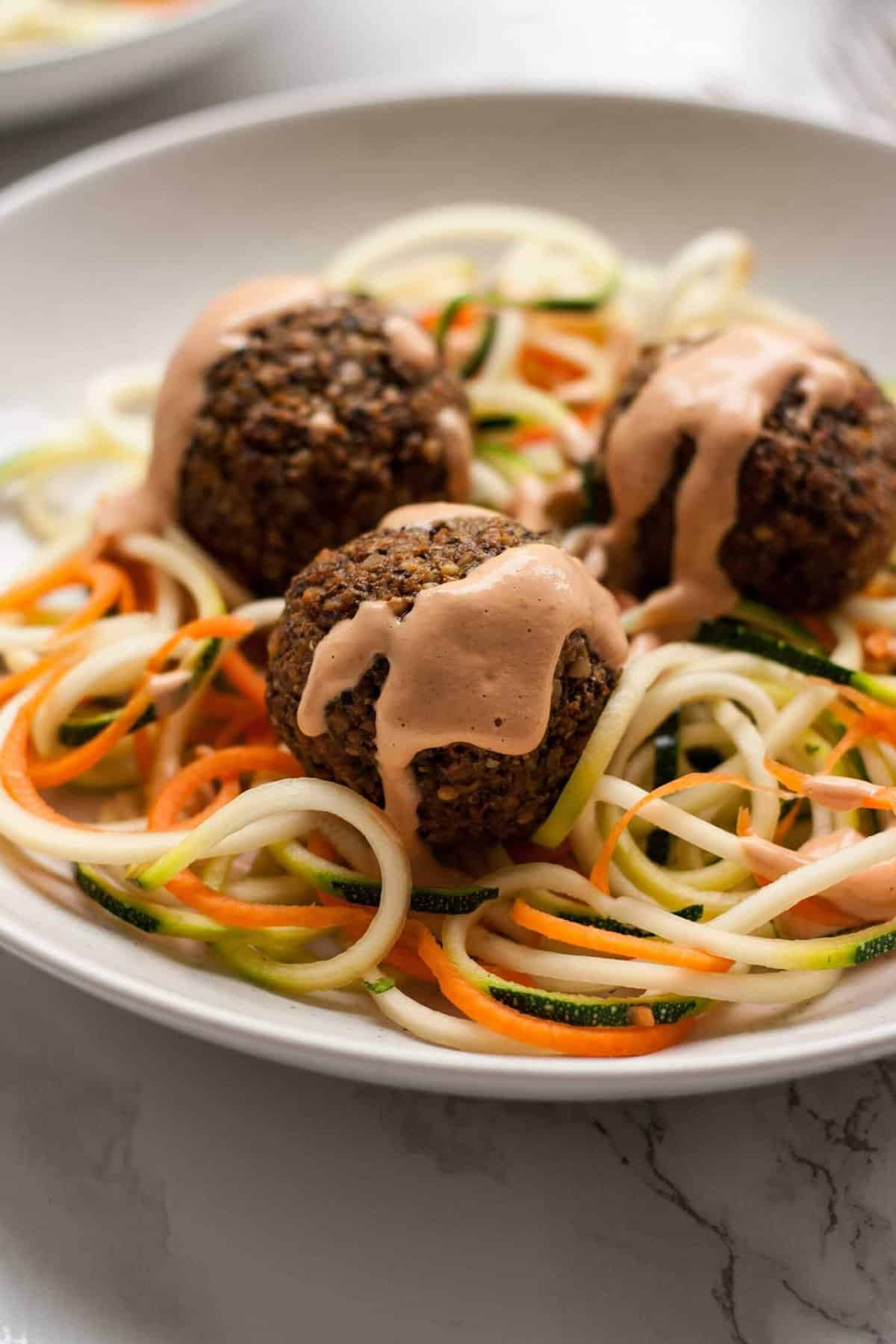 Close up of sauce over the vegan meatballs on zoodles.