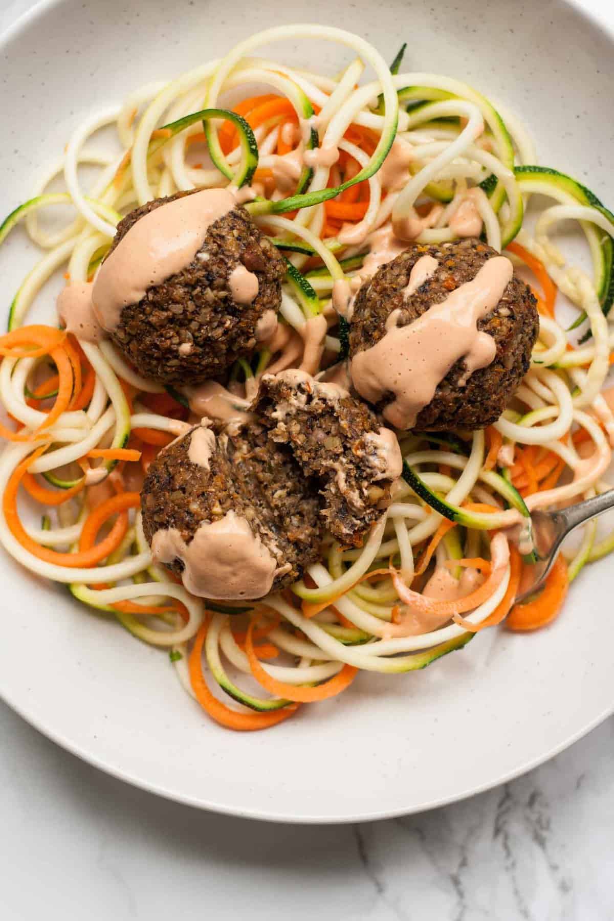 Close up overhead of broken open vegan meatball with sauce over the top.