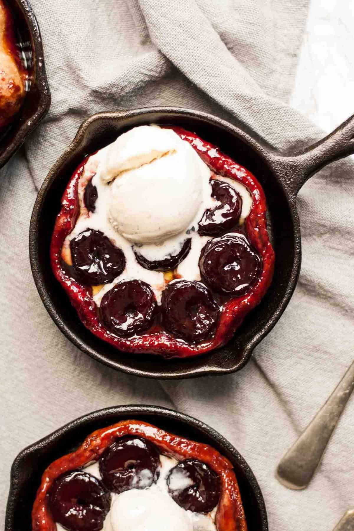 A close up of a cherry tarte tatin with vanilla ice cream melting on top.