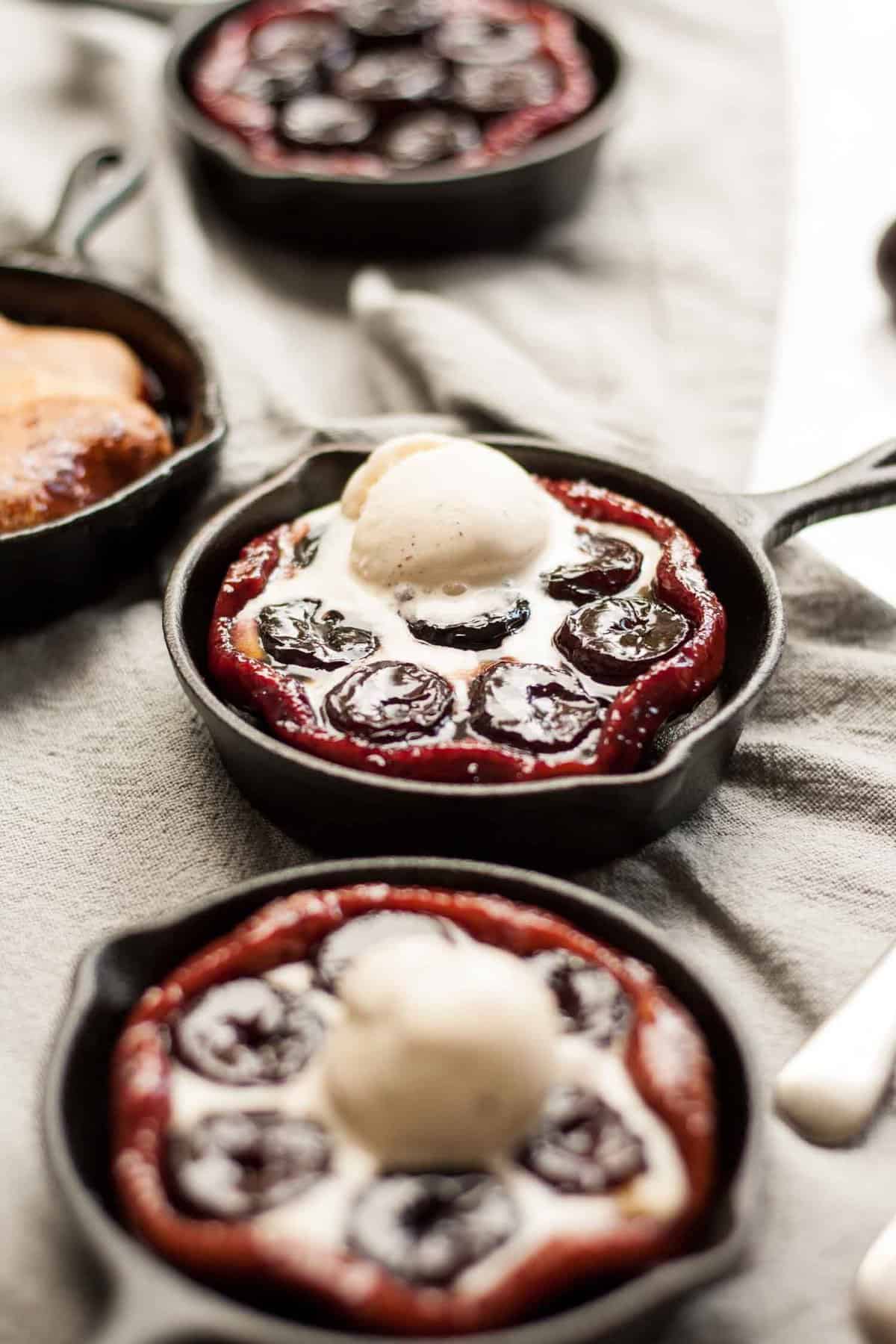 Close up of cherry tarte tatin with vanilla ice cream melting on top in a skillet.