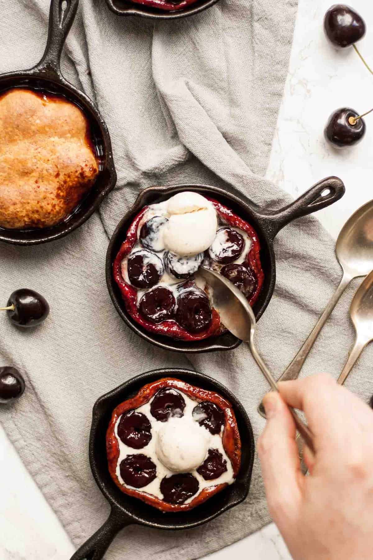 three cherry tarte tatin with someone dipping a spoon into it.