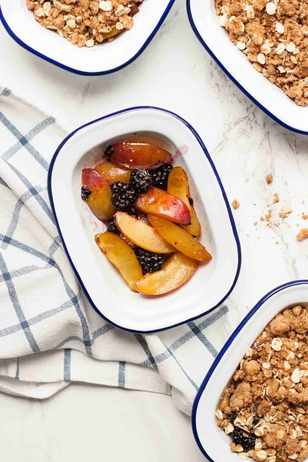 A pie dish with plums and blackberries without a crumble topping.
