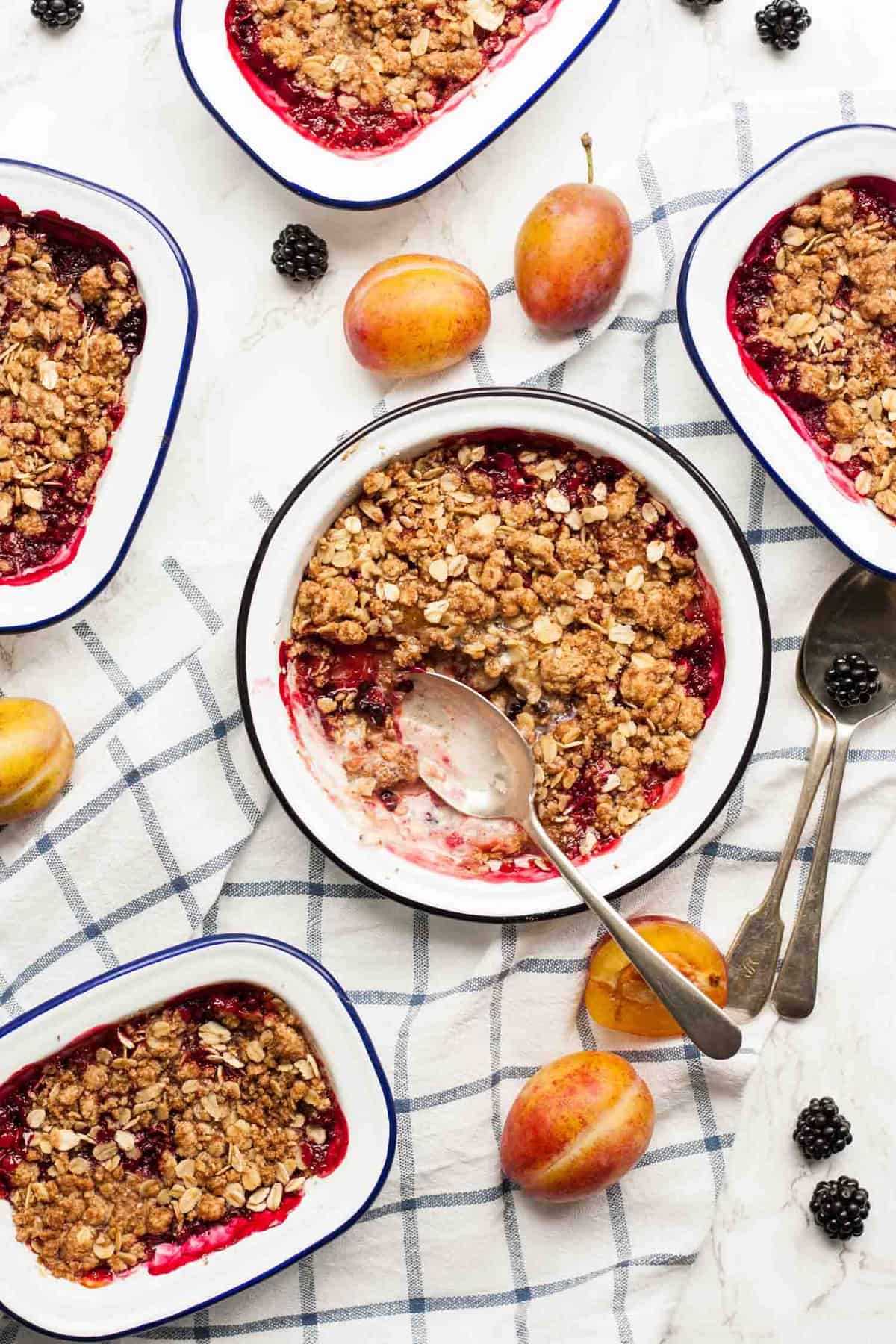 A dish of fruit crisp with a portion eaten from it. 