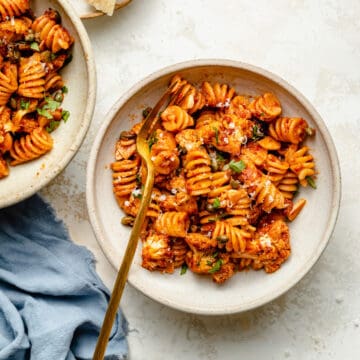 Nduja Pasta with roasted cauliflower served in a bowl with a golden fork and a napkin.