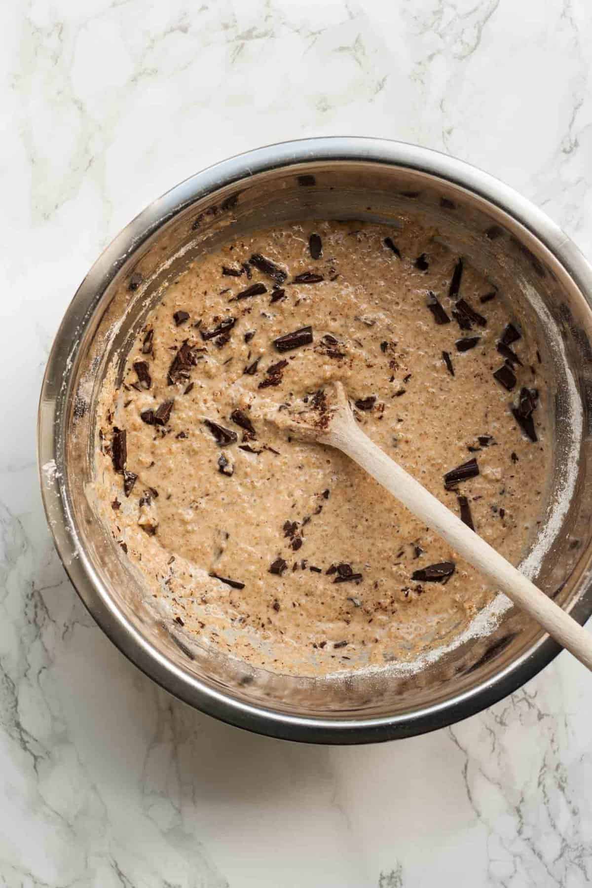 blueberry muffin batter in a metal bowl with a wooden spoon.