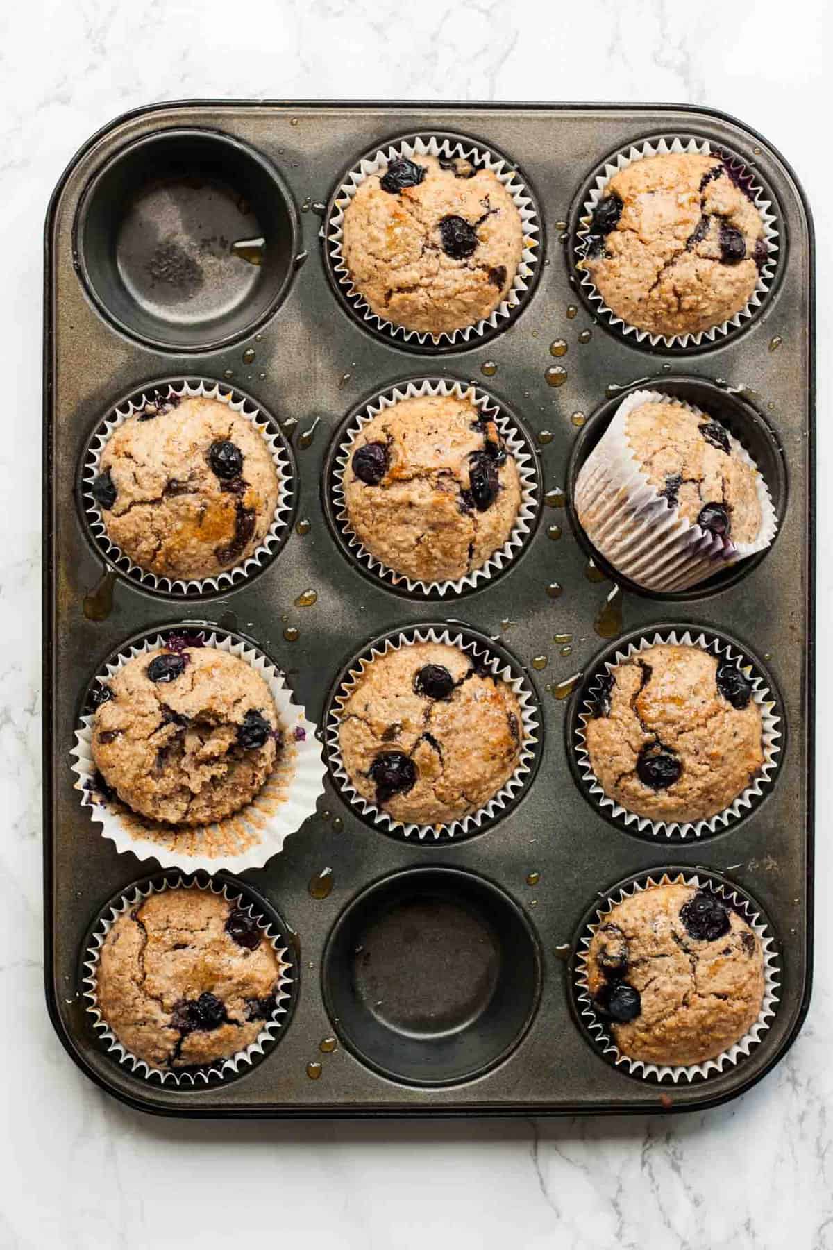 A muffin baking sheet with blueberry breakfast muffins in it.