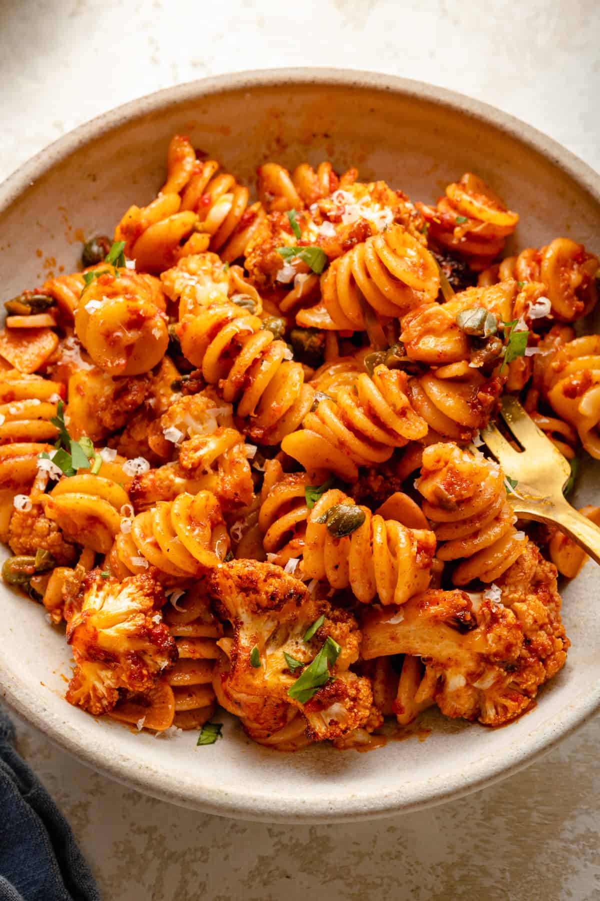 A close up of a bowl of nduja pasta with roasted cauliflower with a fork.