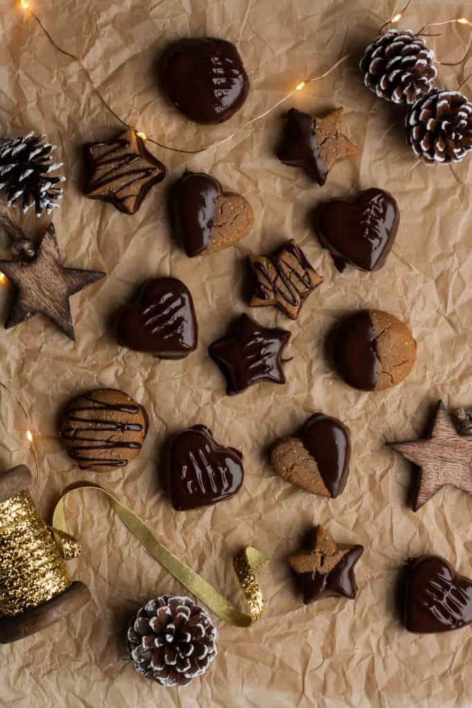 Chocolate Lebkuchen cookies arranged on a tray lined with parchment with lights, ribbon and decorations around. 