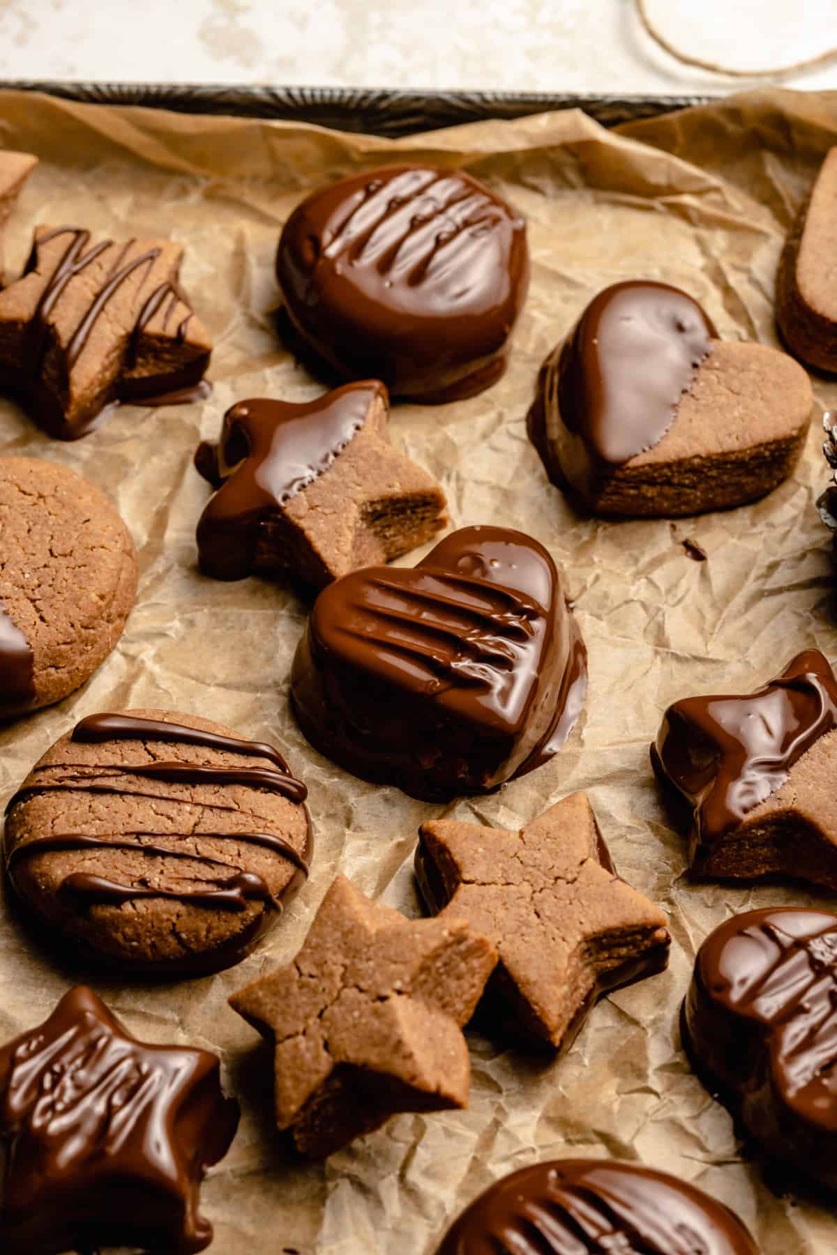 Chocolate coated lebkuchen cookies on a tray on parchment paper with drizzles of chocolate on top.