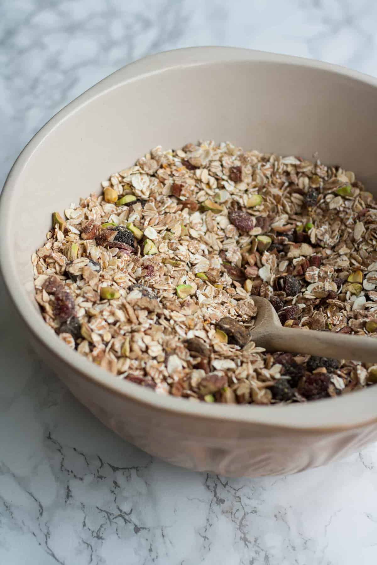 A bowl of museli having been mixed together with a wooden spoon.