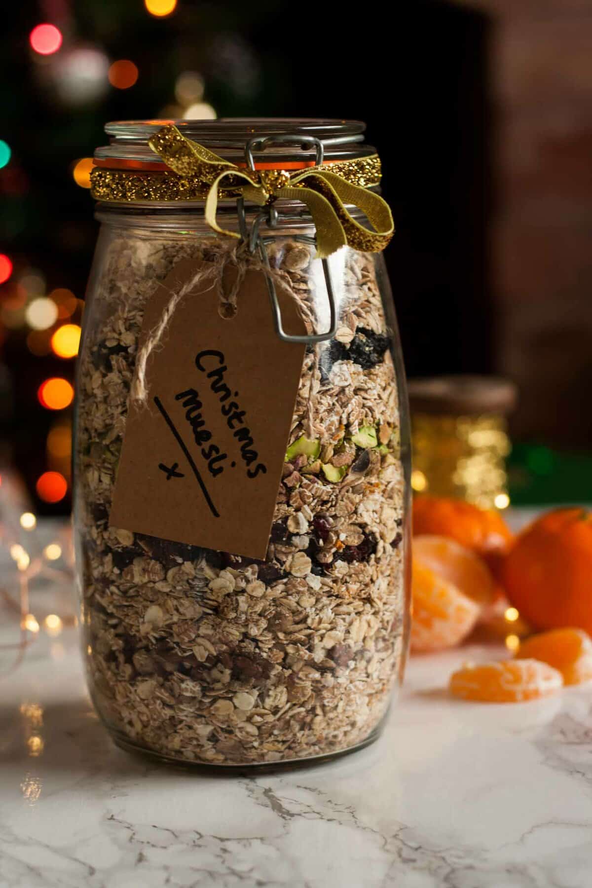 Christmas muesli in a jar with a ribbon around it and lights in the background.