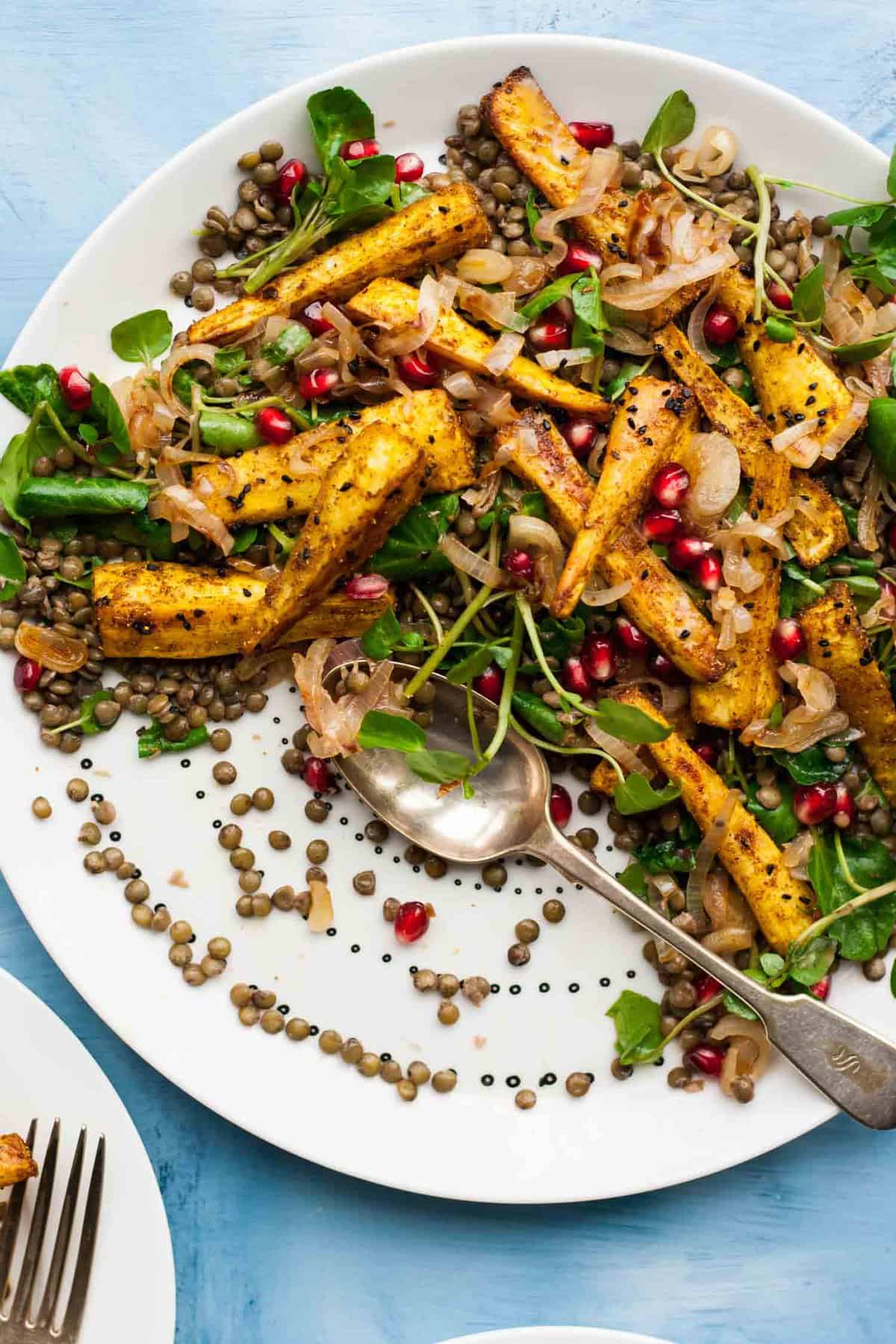 A platter of parsnip and lentil salad served up with a messy spoon on it.