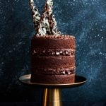 A triple layered chocolate rocky road layer cake with shards of rocky road on top.