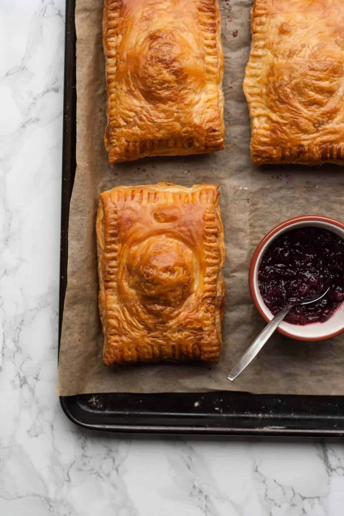 Close up of baked turkey pastries with cranberry sauce in a bowl.