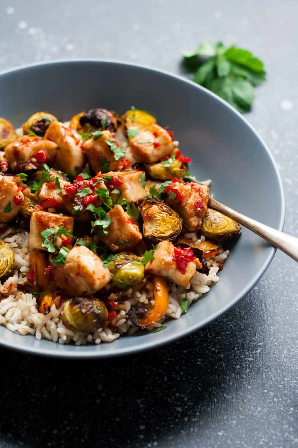 Close up of sweet chilli halloumi brussels sprouts in a bowl with a fork.