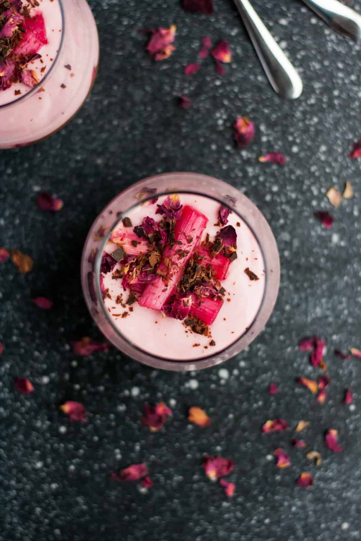 Close shot of rhubarb, chocolate and rose petals on top of rhubarb parfait in a glass.