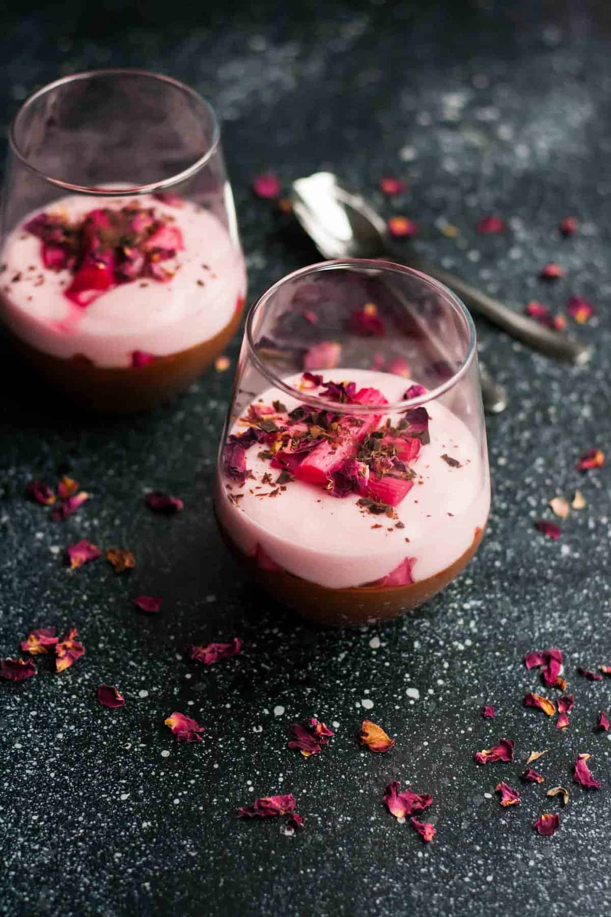 Two glasses containing a multilayered rhubarb and dark chocolate parfait with rhubarb on top.