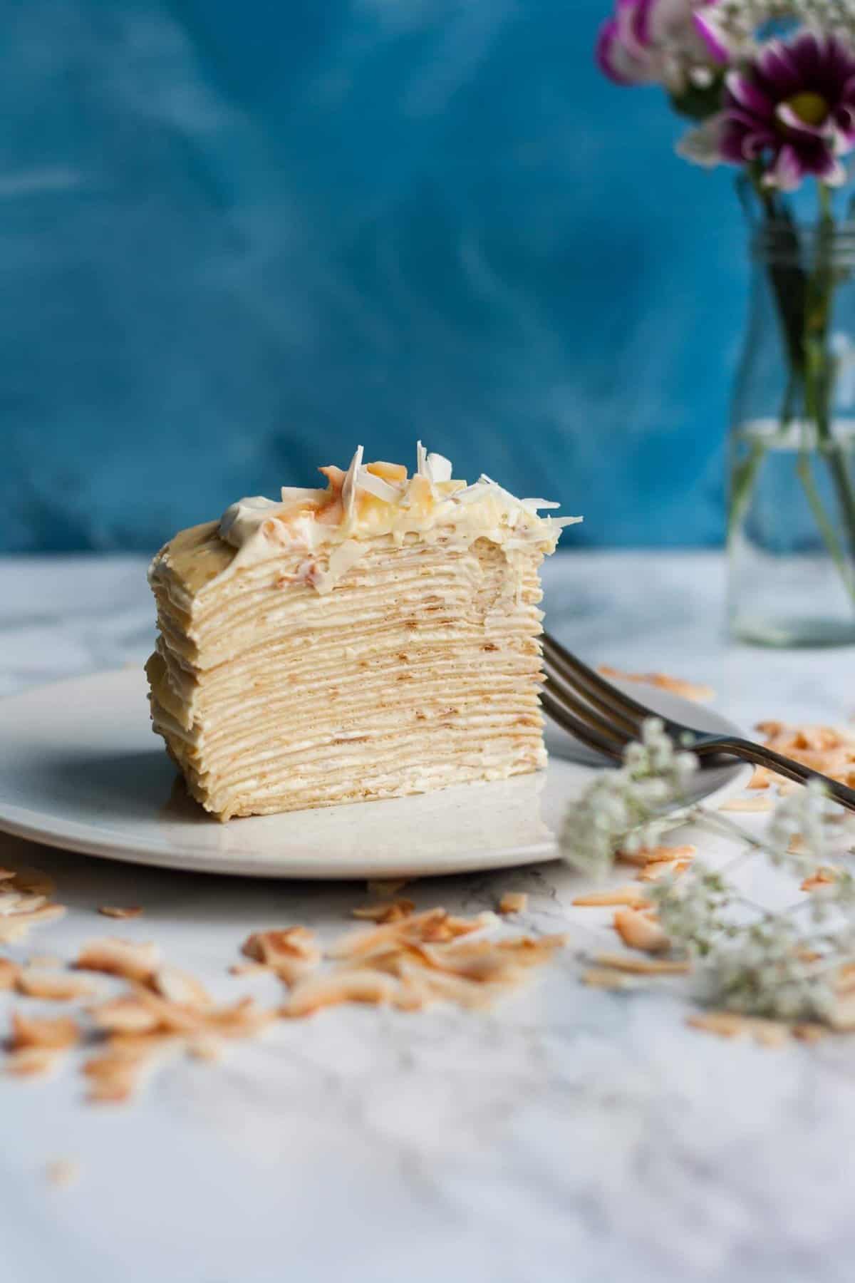 A layered wedge of crepe cake on a plate with a fork.