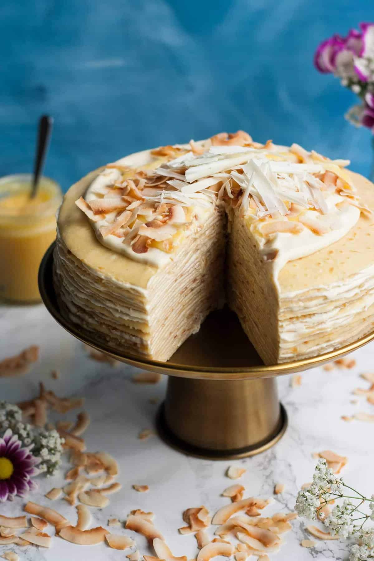A lemon curd crepe cake with a wedge cut out of it. 