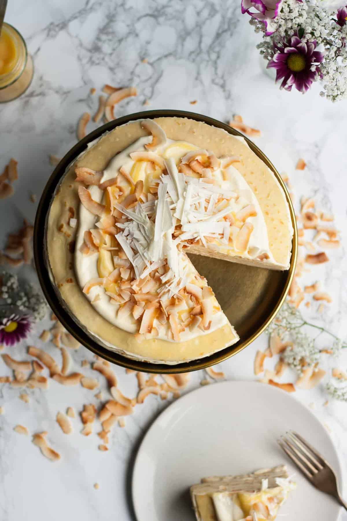 A cake with a wedge cut open with toasted coconut around.