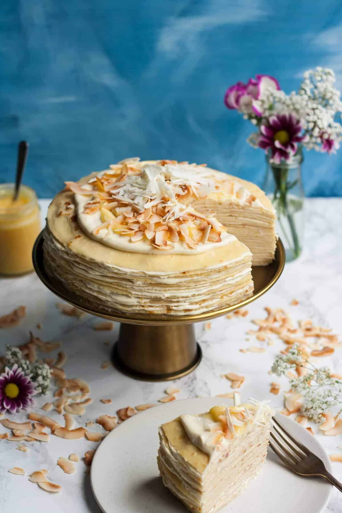 A wedge cut out of a crepe cake on a cake stand.