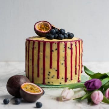 A blueberry and passionfruit cake with blueberries and passionfruit around.
