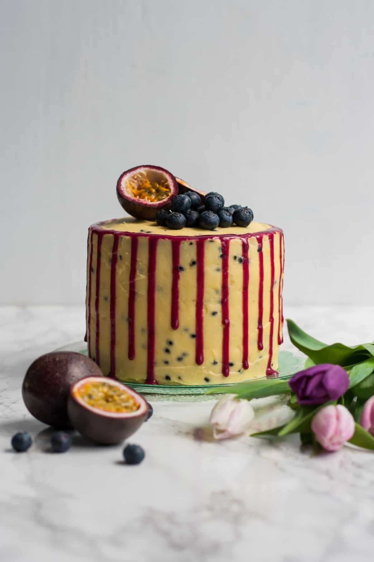 A blueberry and passionfruit cake with blueberries and passionfruit around.