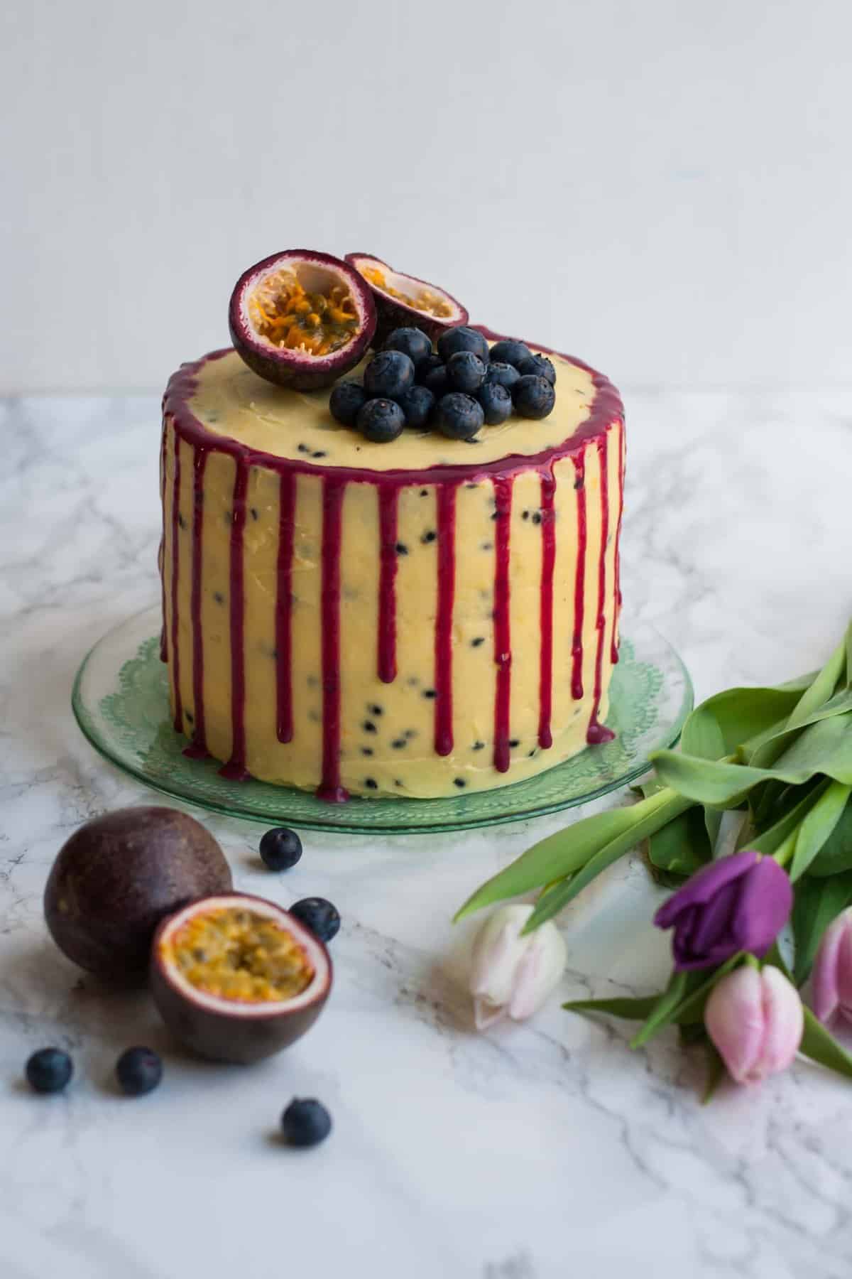 A blueberry passionfruit layer cake with with blueberries and passionfruit on top.