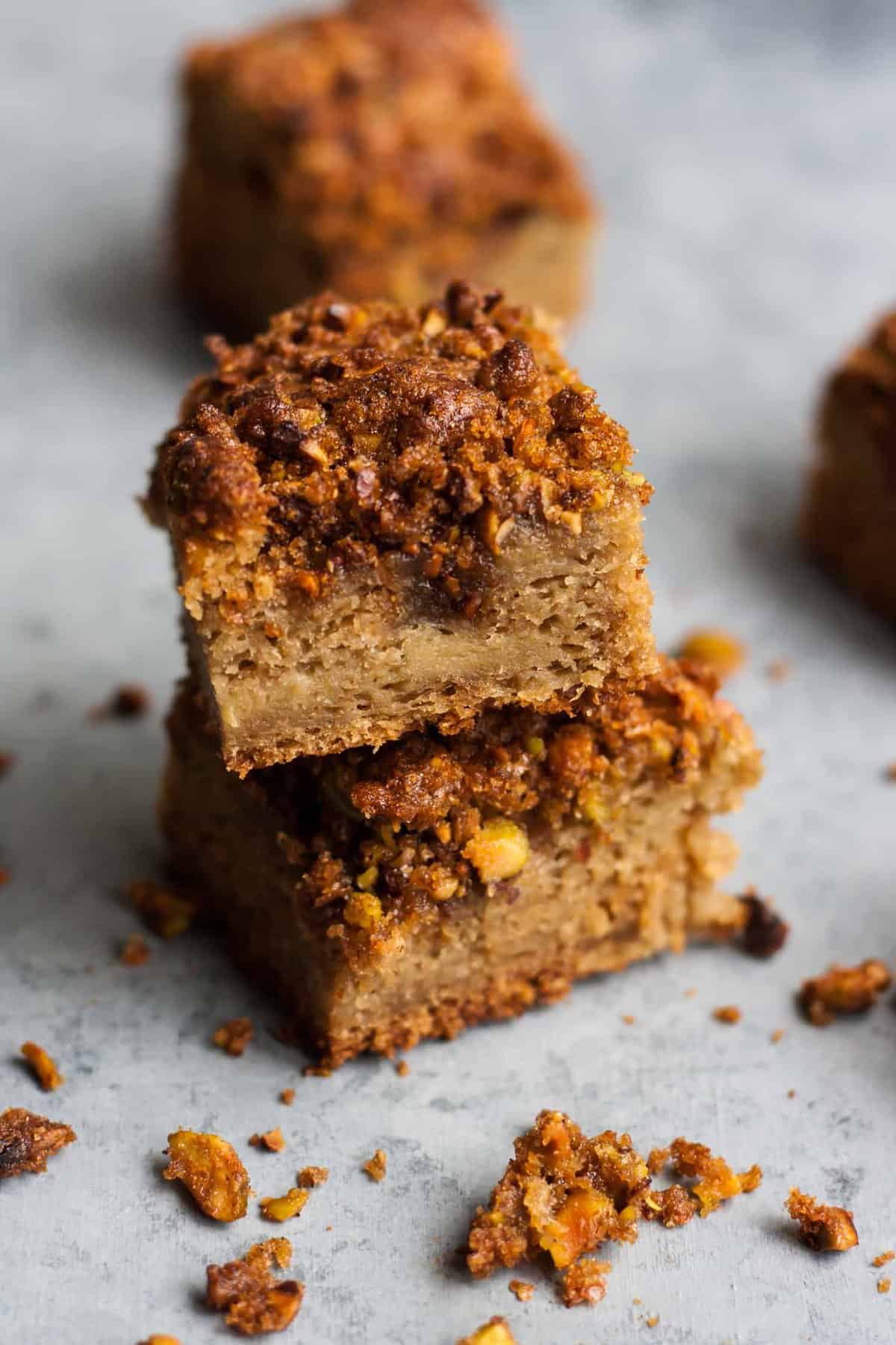 A stack of two squares of cake with crumbs around it. 