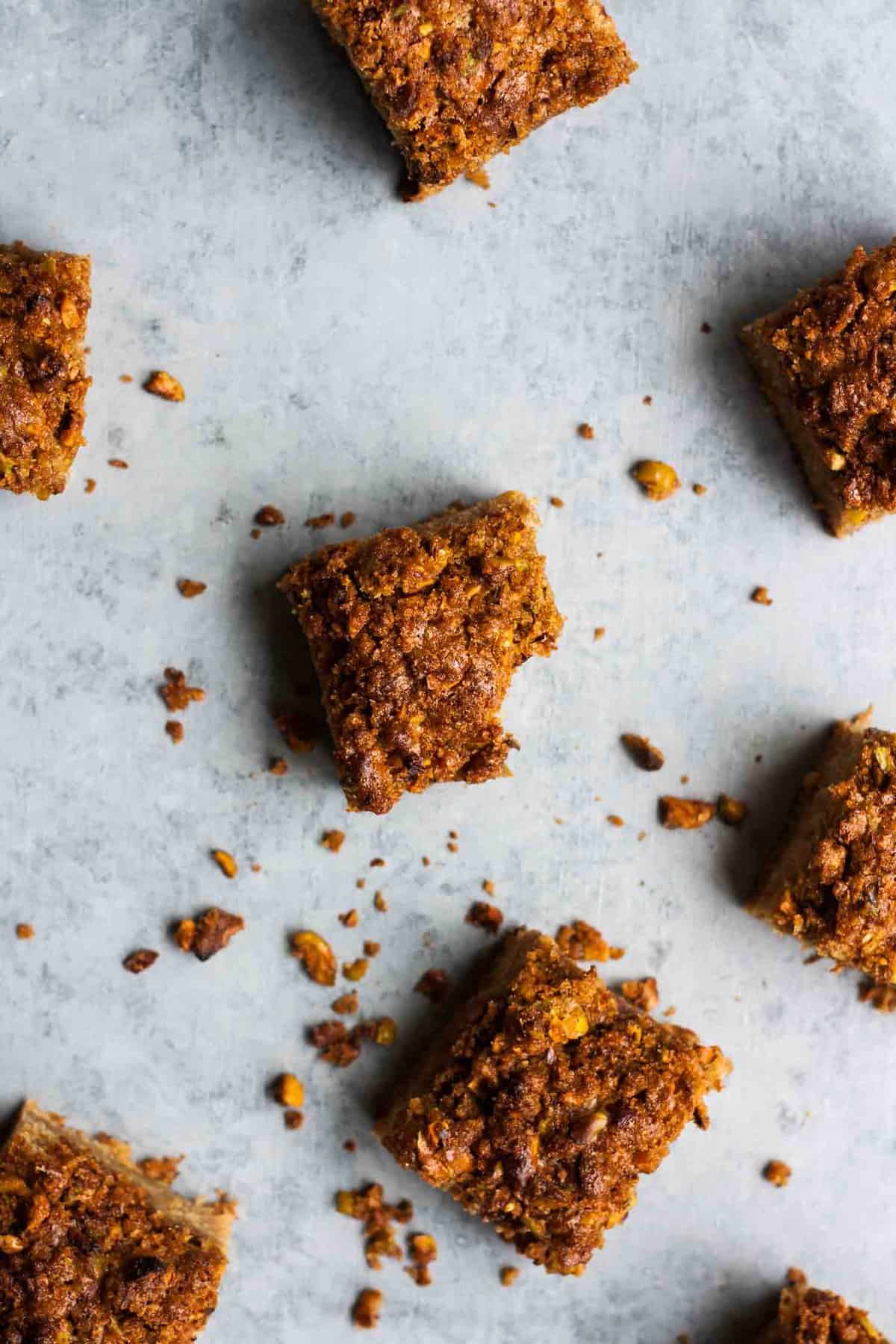 An array of rhubarb yoghurt cake squares, one with a bite taken out and crumbs around.