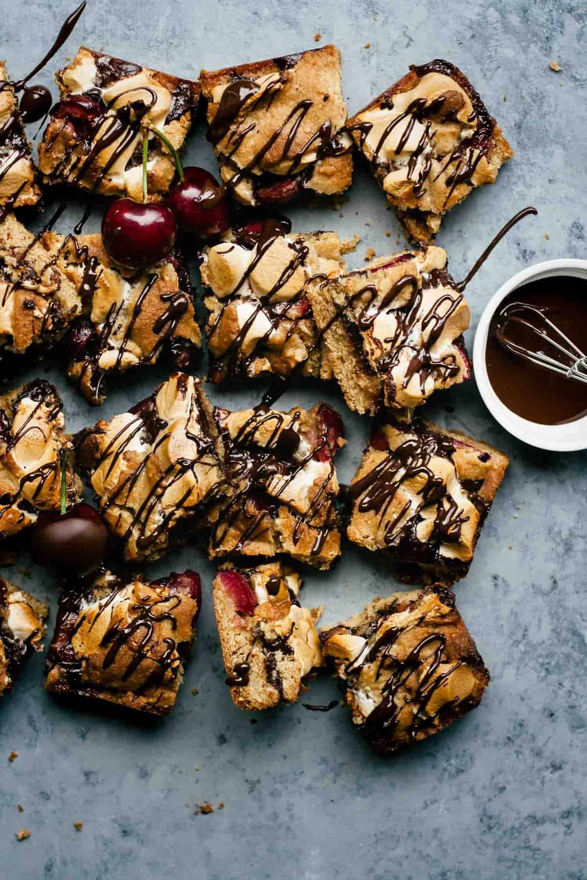 Chocolate cherry s\'mores bars cut into squares with melted chocolate drizzled on top.