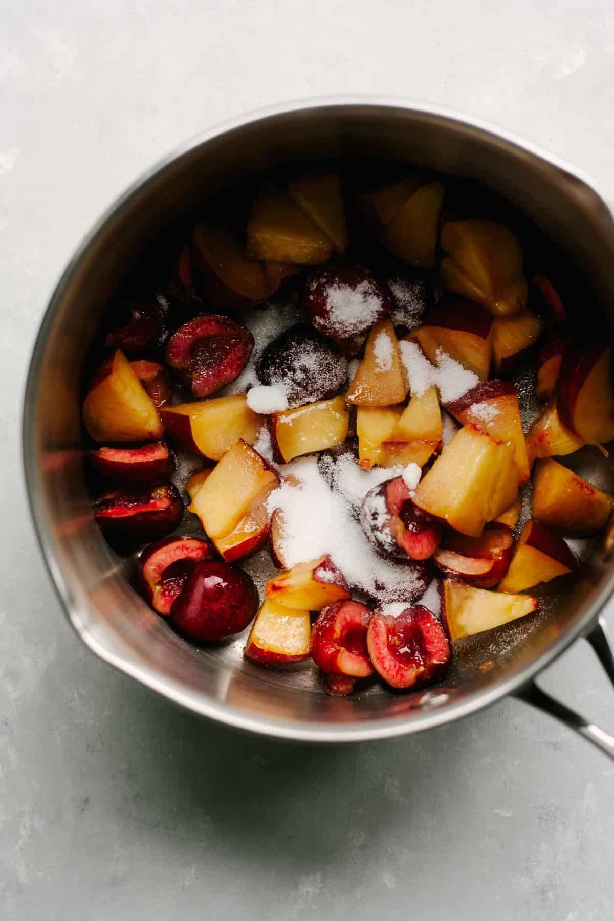 A saucepan of fruit, with sugar on top. 