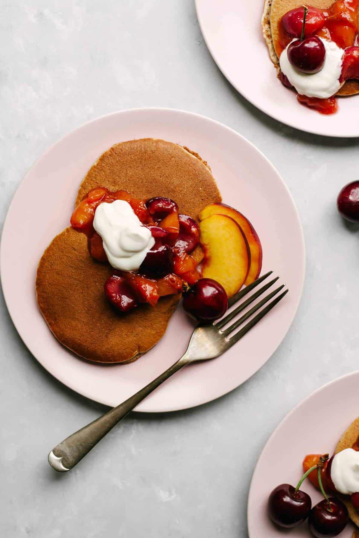 A plate of pancakes with compote and yoghurt on top.