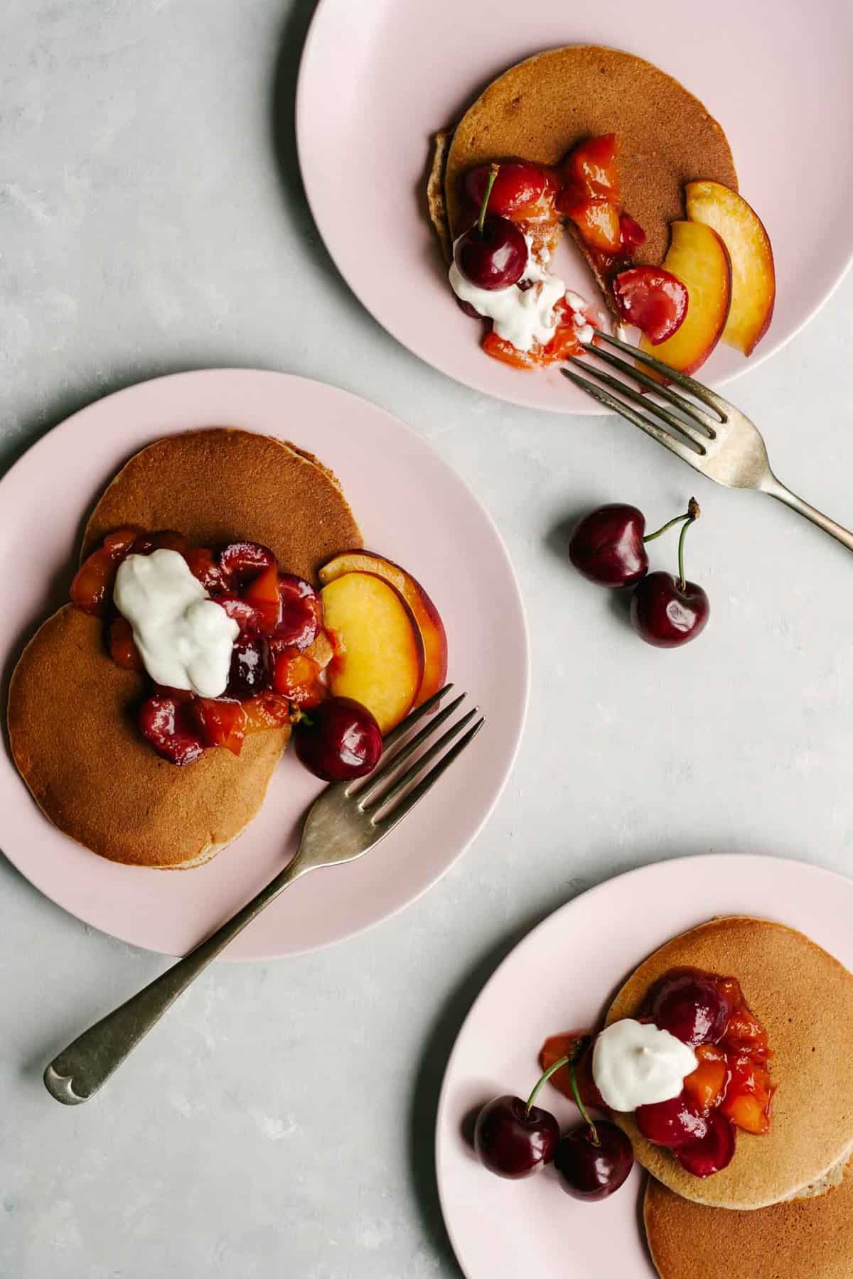 Plates with Almond butter pancakes and compote and forks.