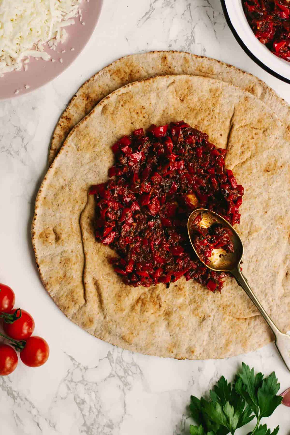 Harissa being spread on flatbread with a spoon.