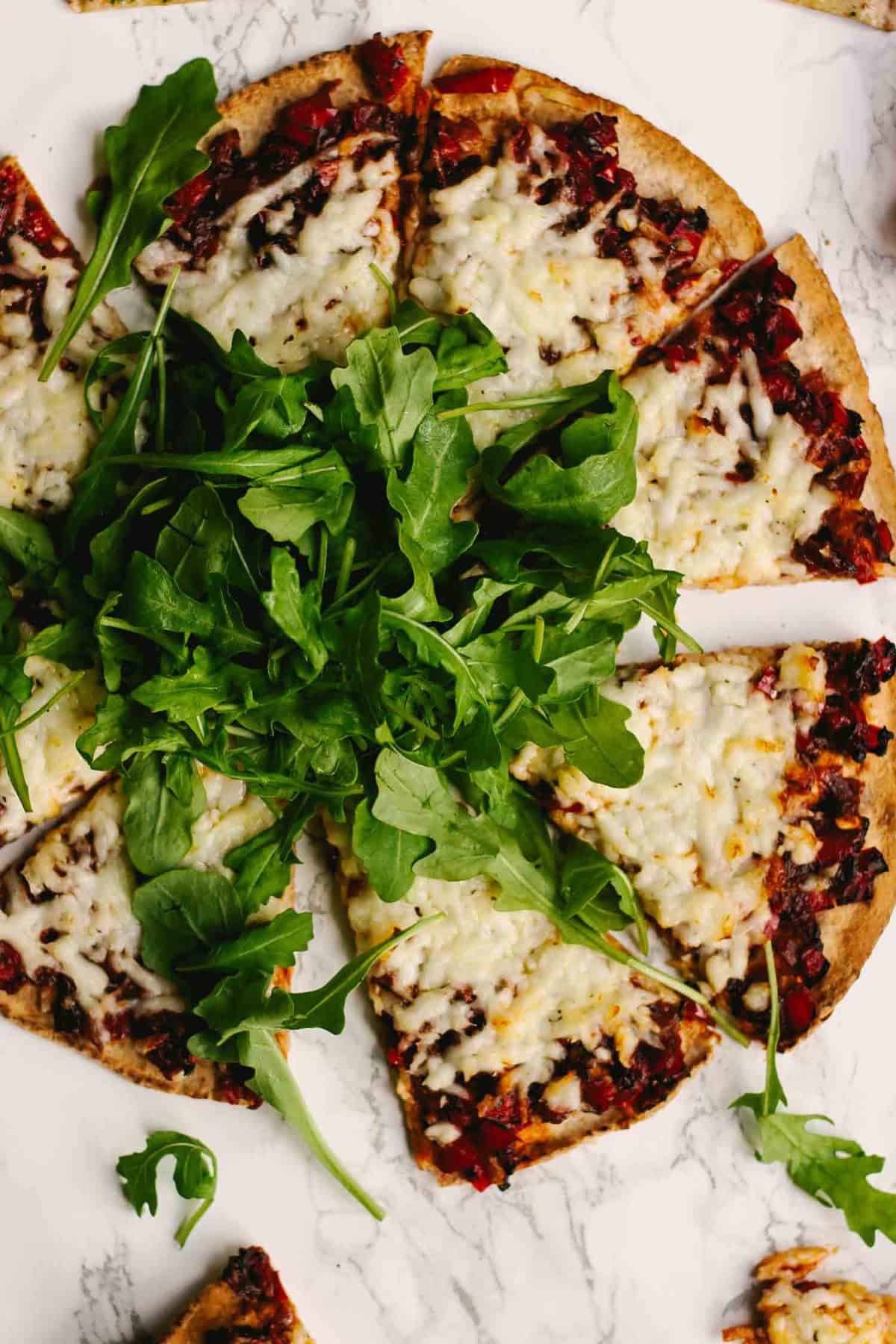 A sliced up halloumi flatbread with arugula on top.