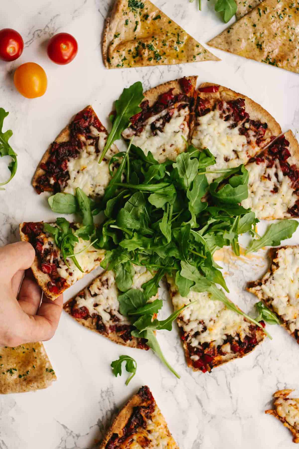 Slices of harissa flatbread with salad and tomato around.