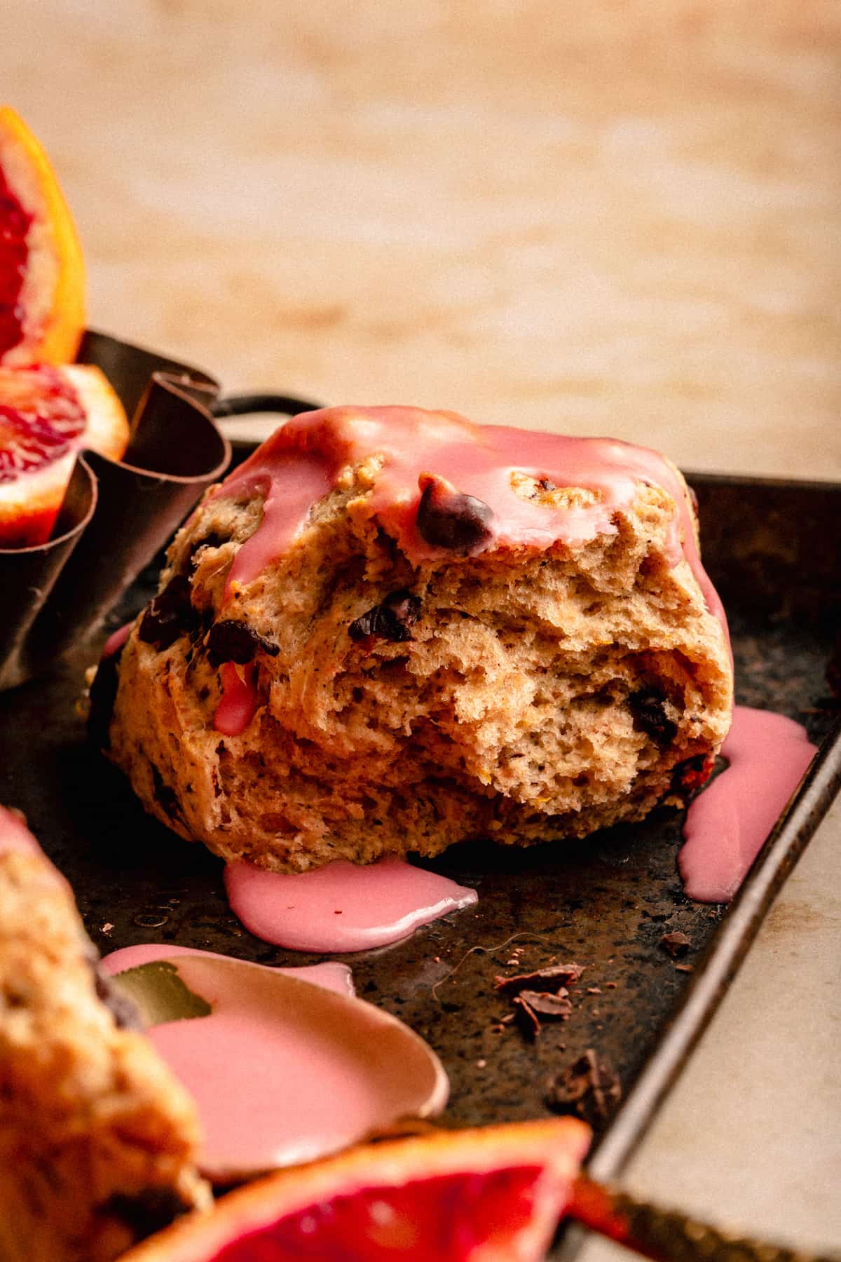 Chocolate Chip Scone glazed with blood orange frosting and broken open showing the fluffy texture.