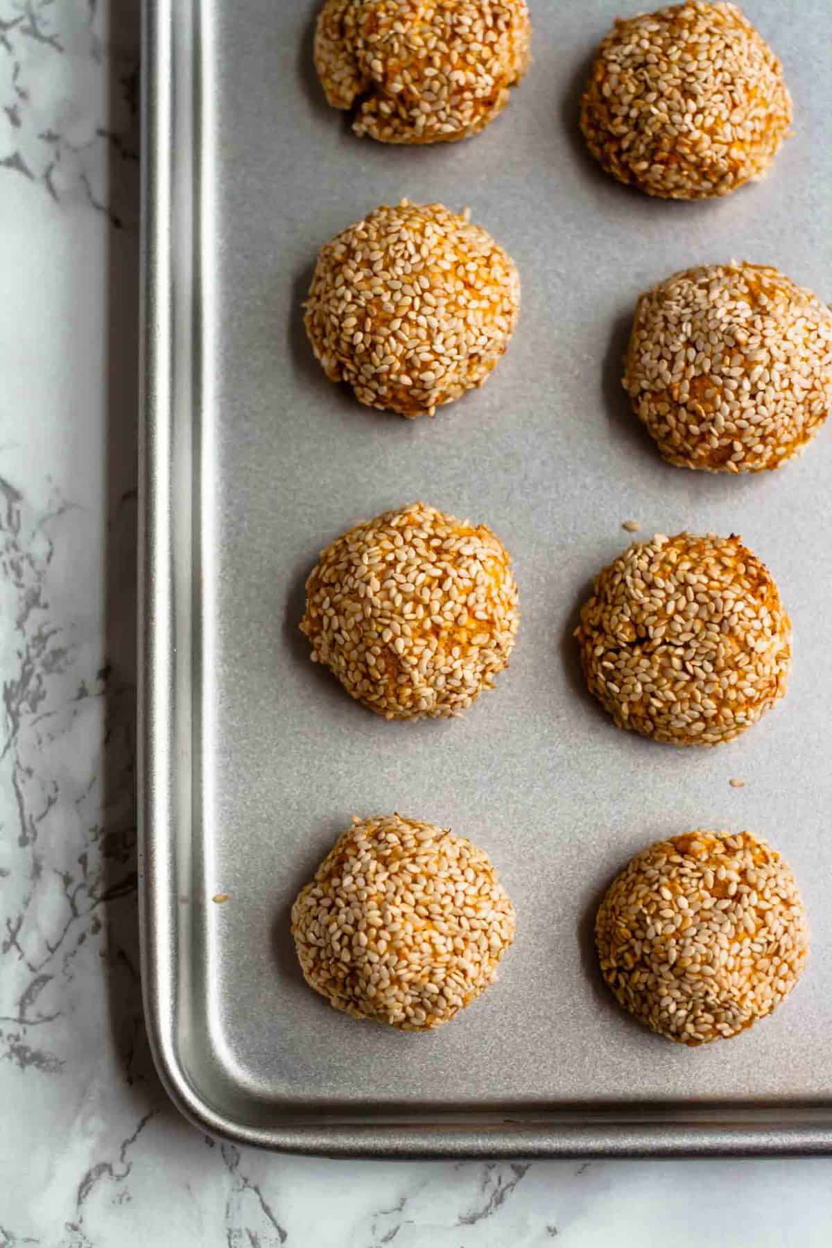 A baking sheet with sweet potato falafel on a marble surface.