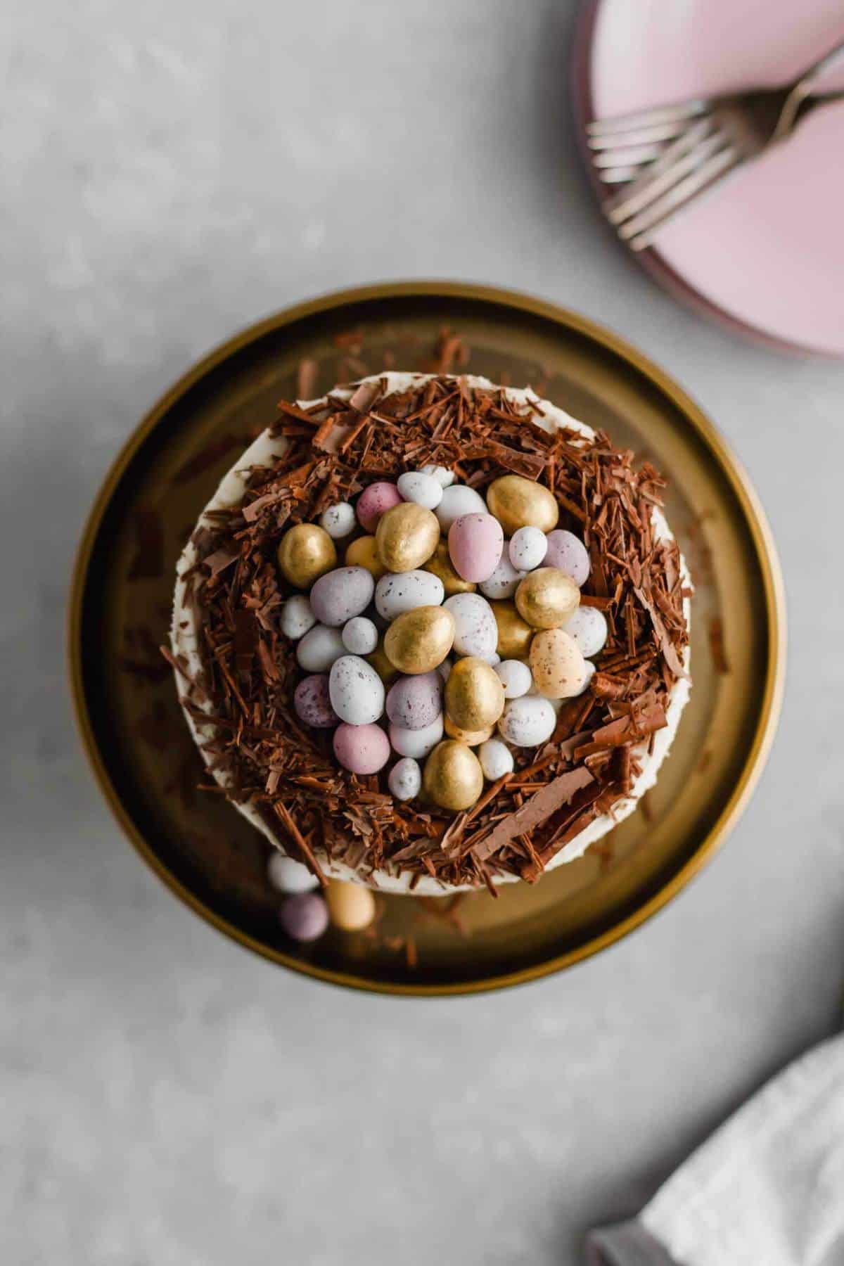 A cake with chocolate shavings on top with a pile of miniature eggs in the middle.