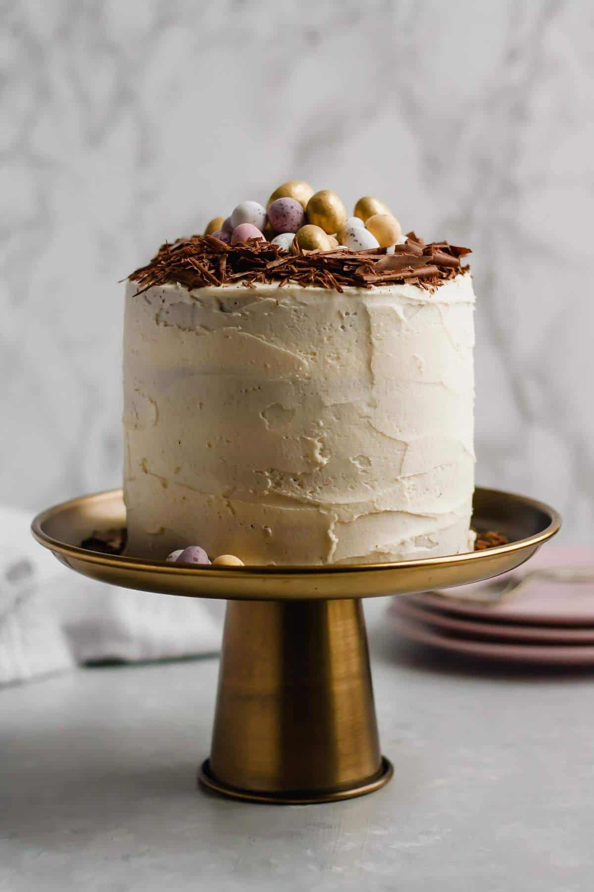 Chocolate chip cake frosted and on a copper cake stand. 