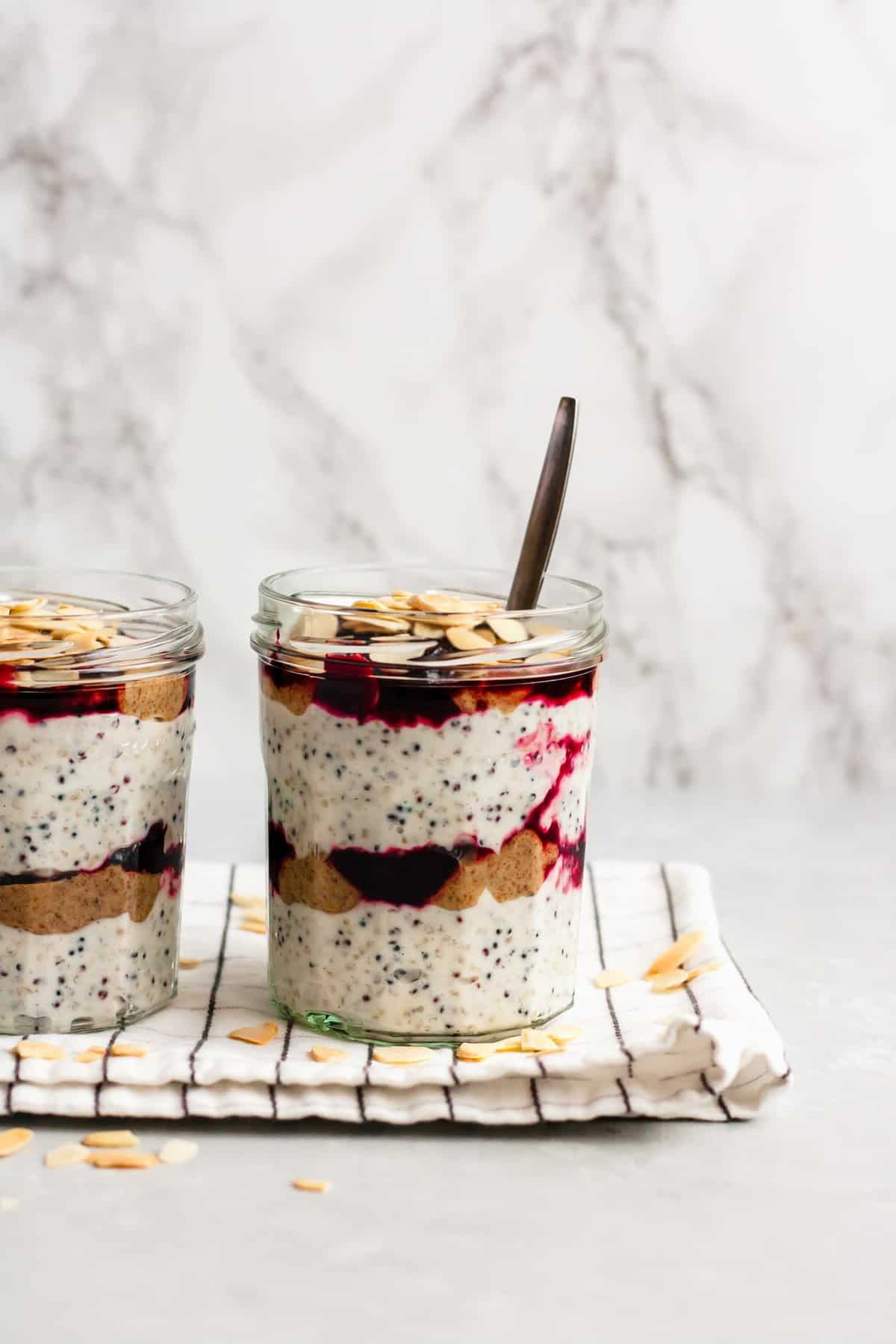 A jar of layered breakfast parfait with a spoon.