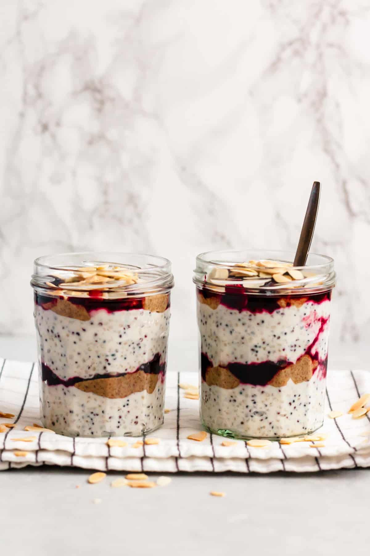 Two jars of cherry breakfast parfaits with a spoon on top of a napkin.