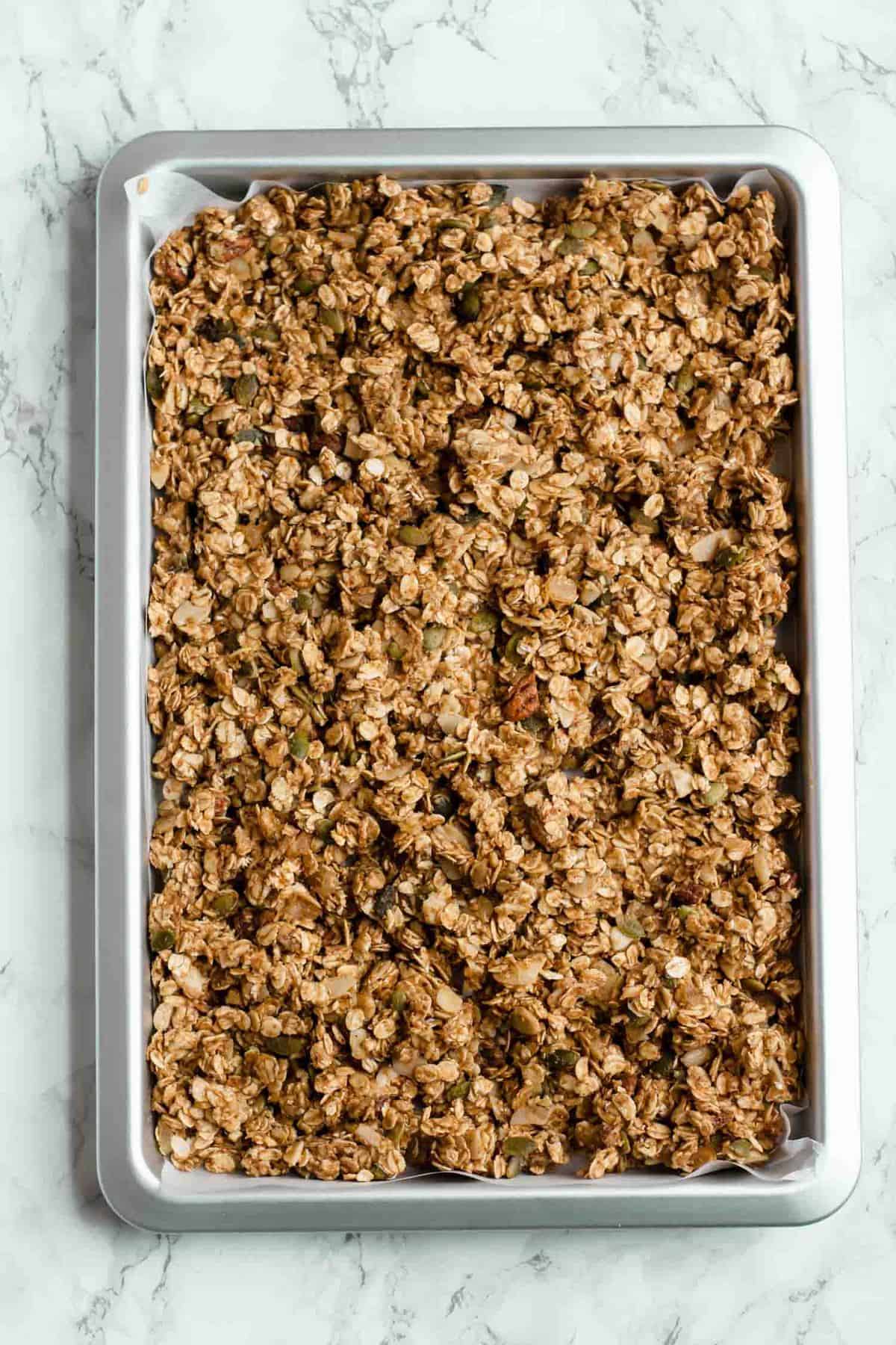 Pre baked granola on a baking sheet.