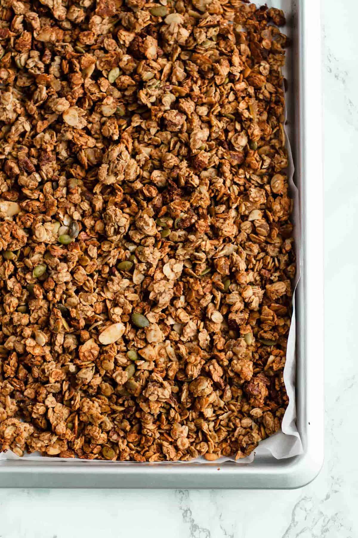 Baked granola on a baking sheet with parchment paper.
