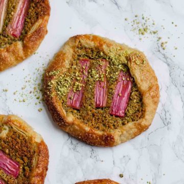 Pistachio frangipane galettes baked on a marble surface.