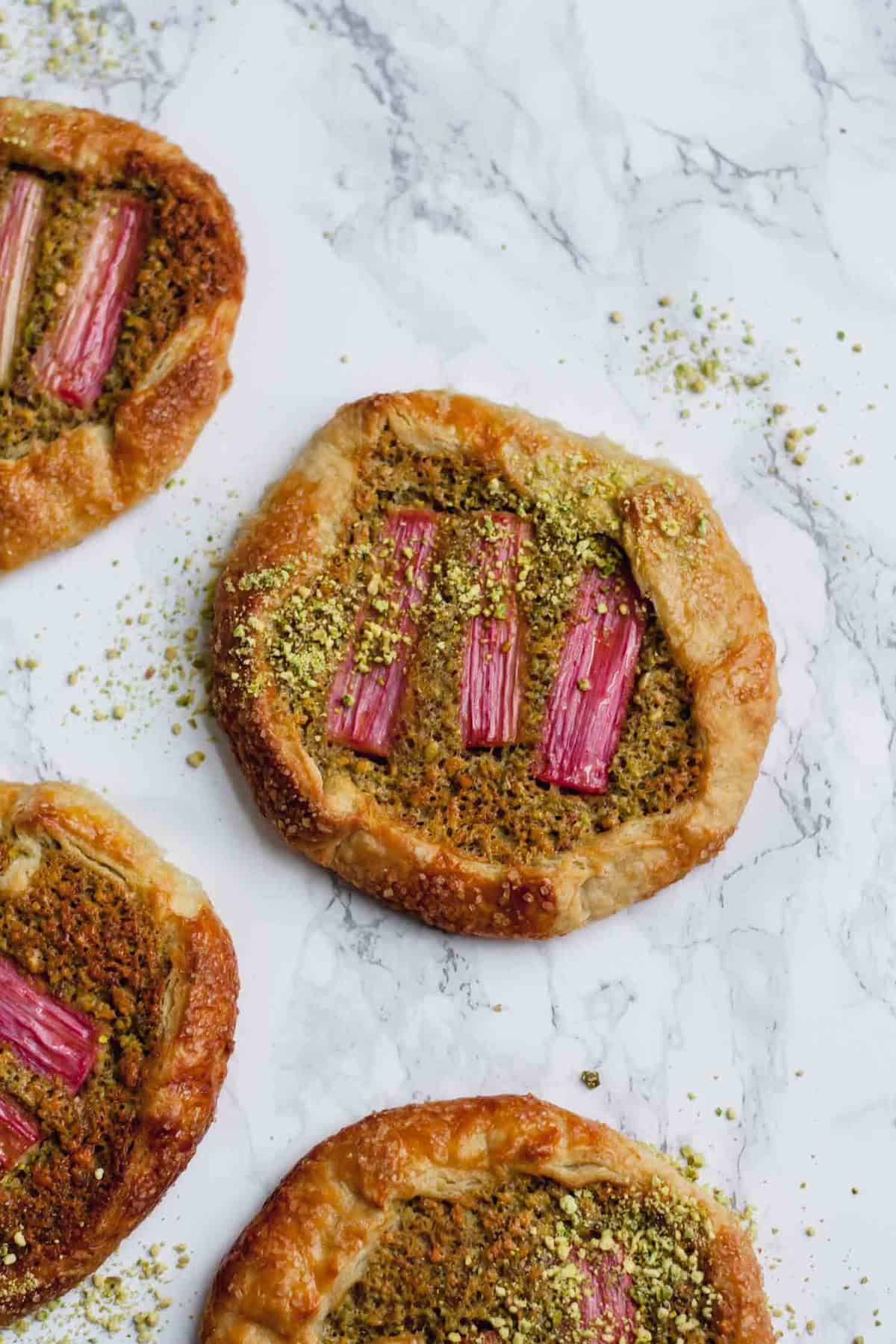 Pistachio frangipane galettes baked on a marble surface.
