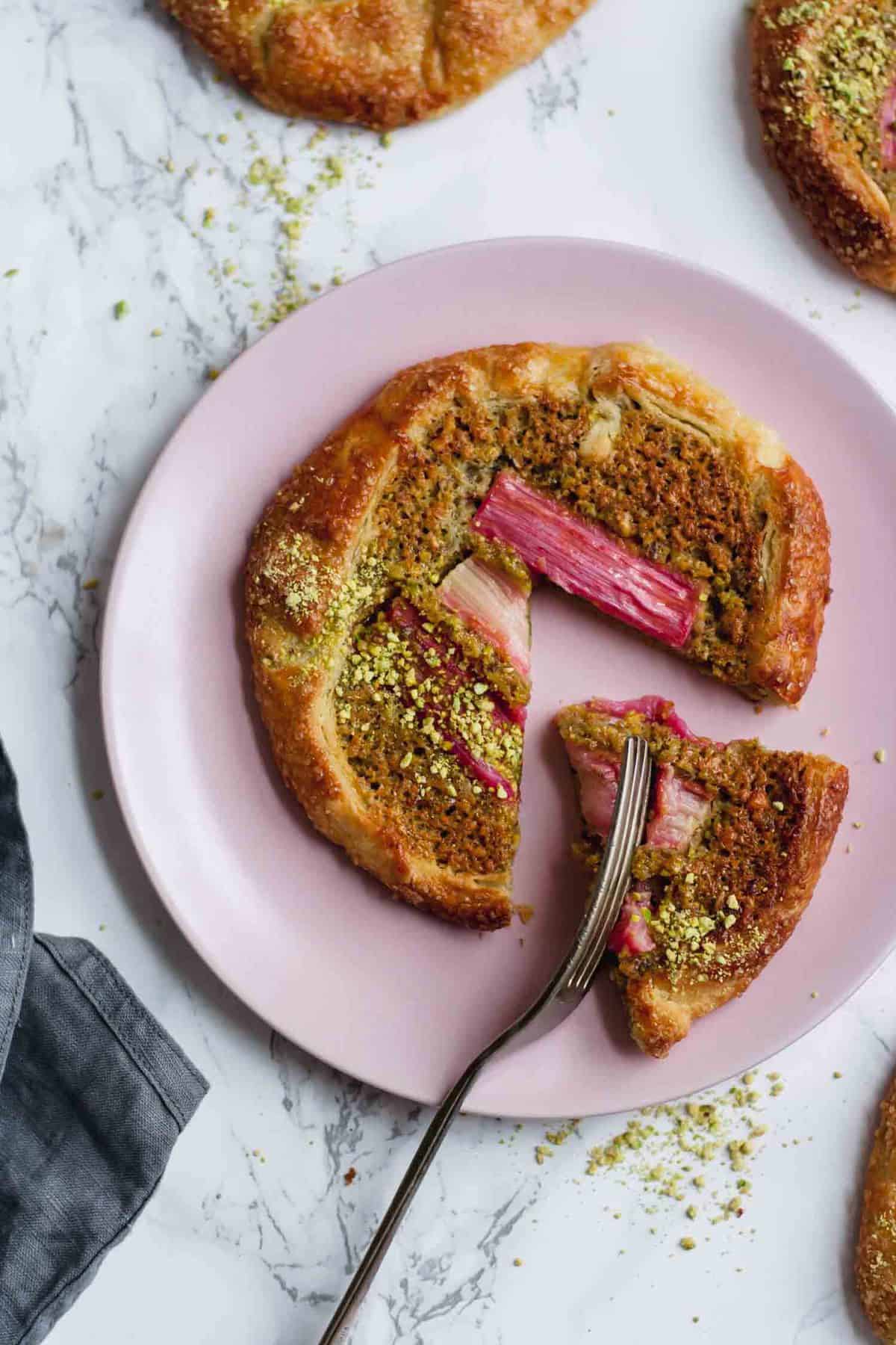 A plate with pistachio galette cut up with a fork. 