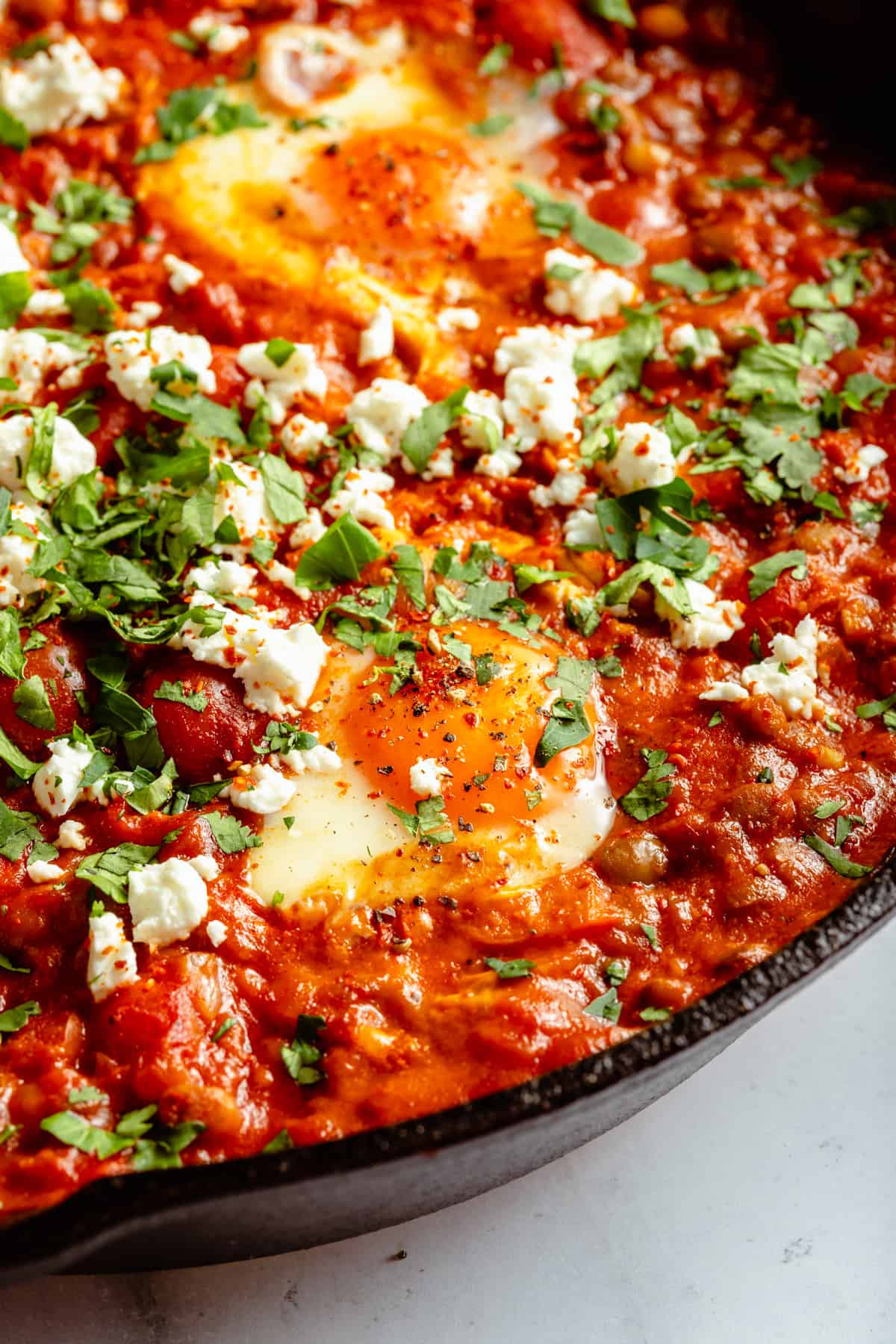 Close up showing the eggs with feta, tomatoes and chorizo around in the sauce. 